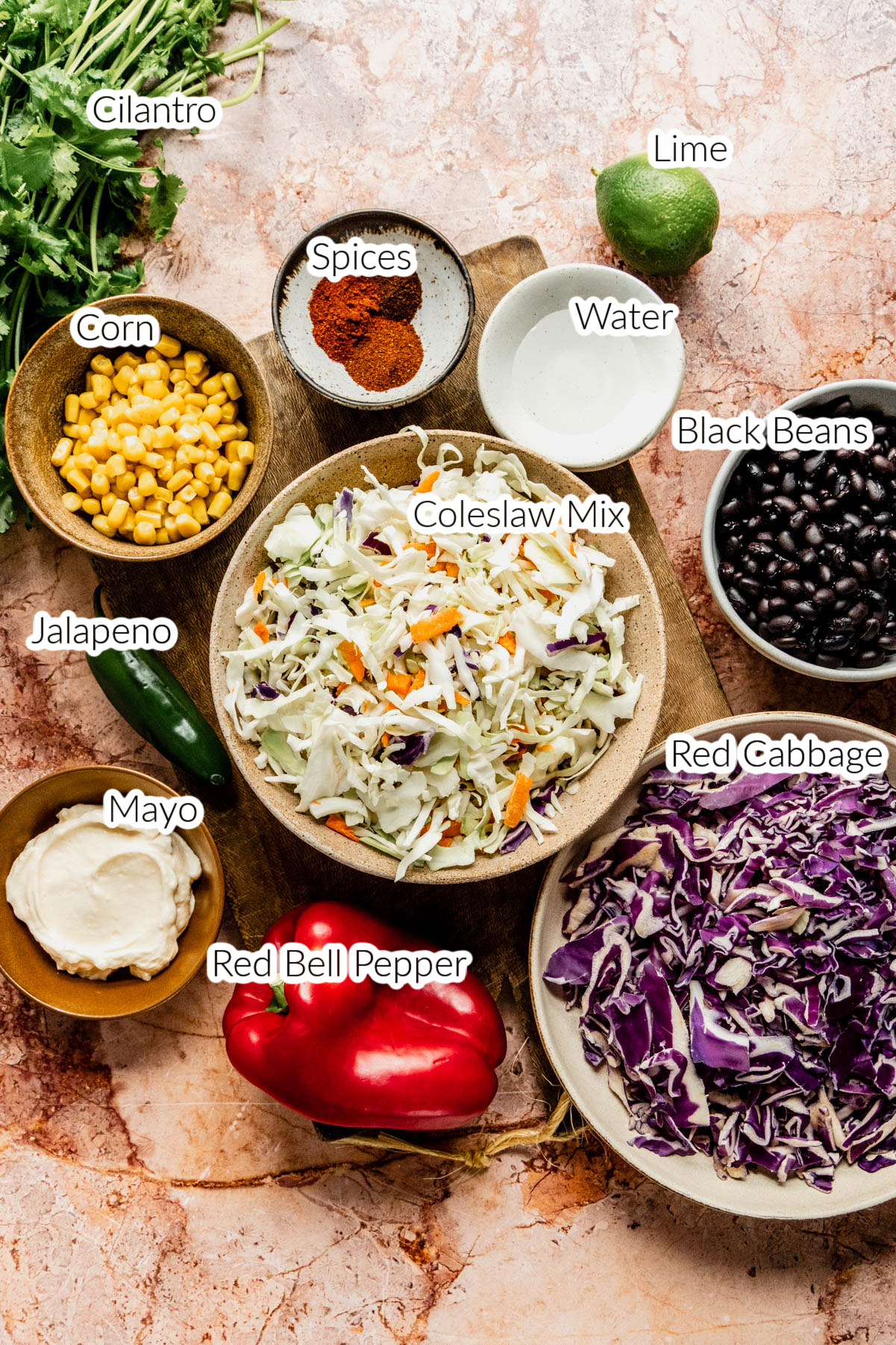 smoky summer slaw ingredients in bowls on brown marble background