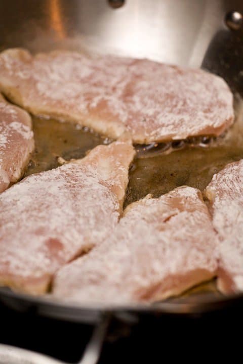 lightly floured chicken breasts in saute pan
