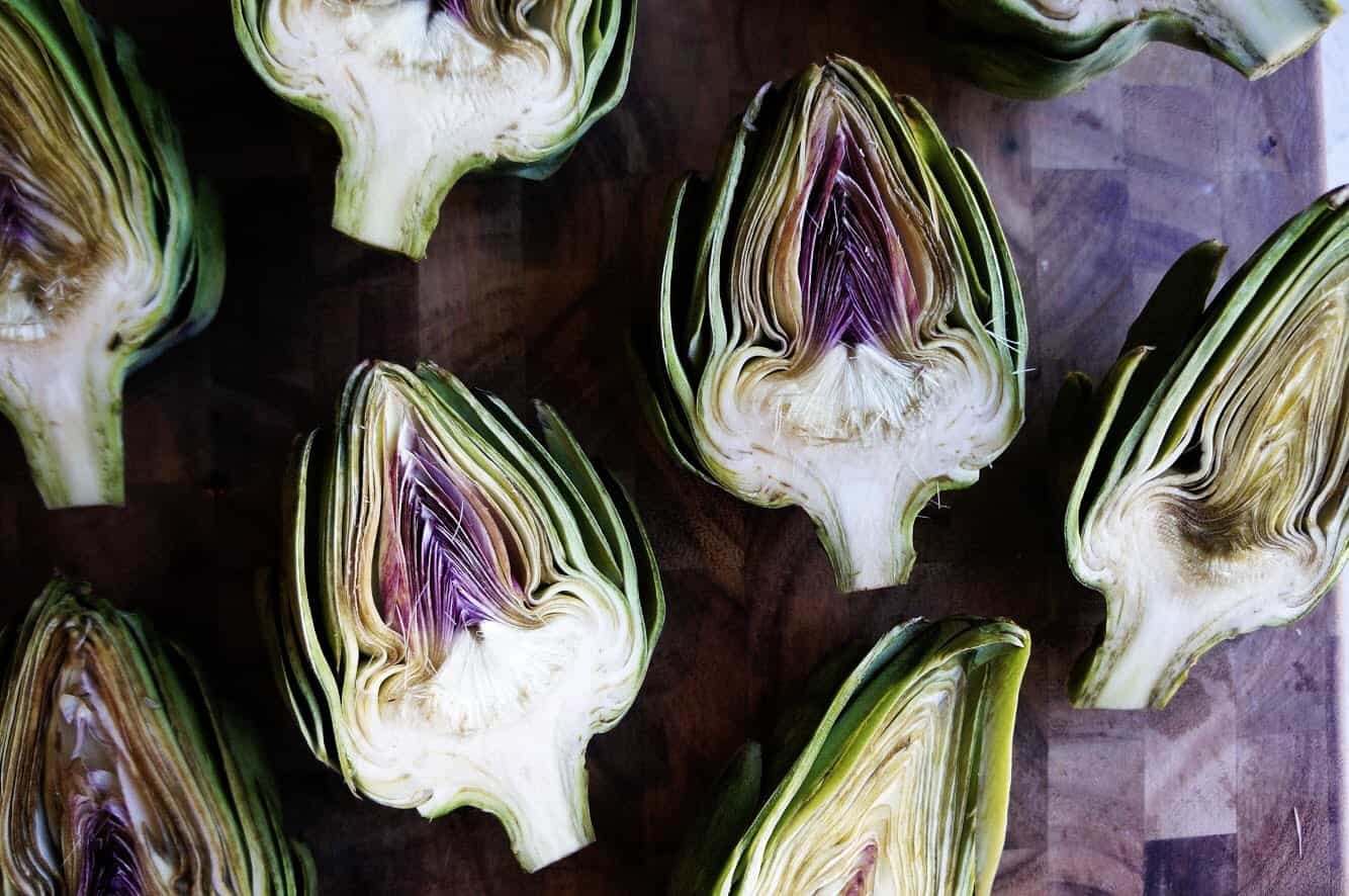 Parmesan Artichoke + White Bean Dip whole Artichokes cut in half on wood cutting board