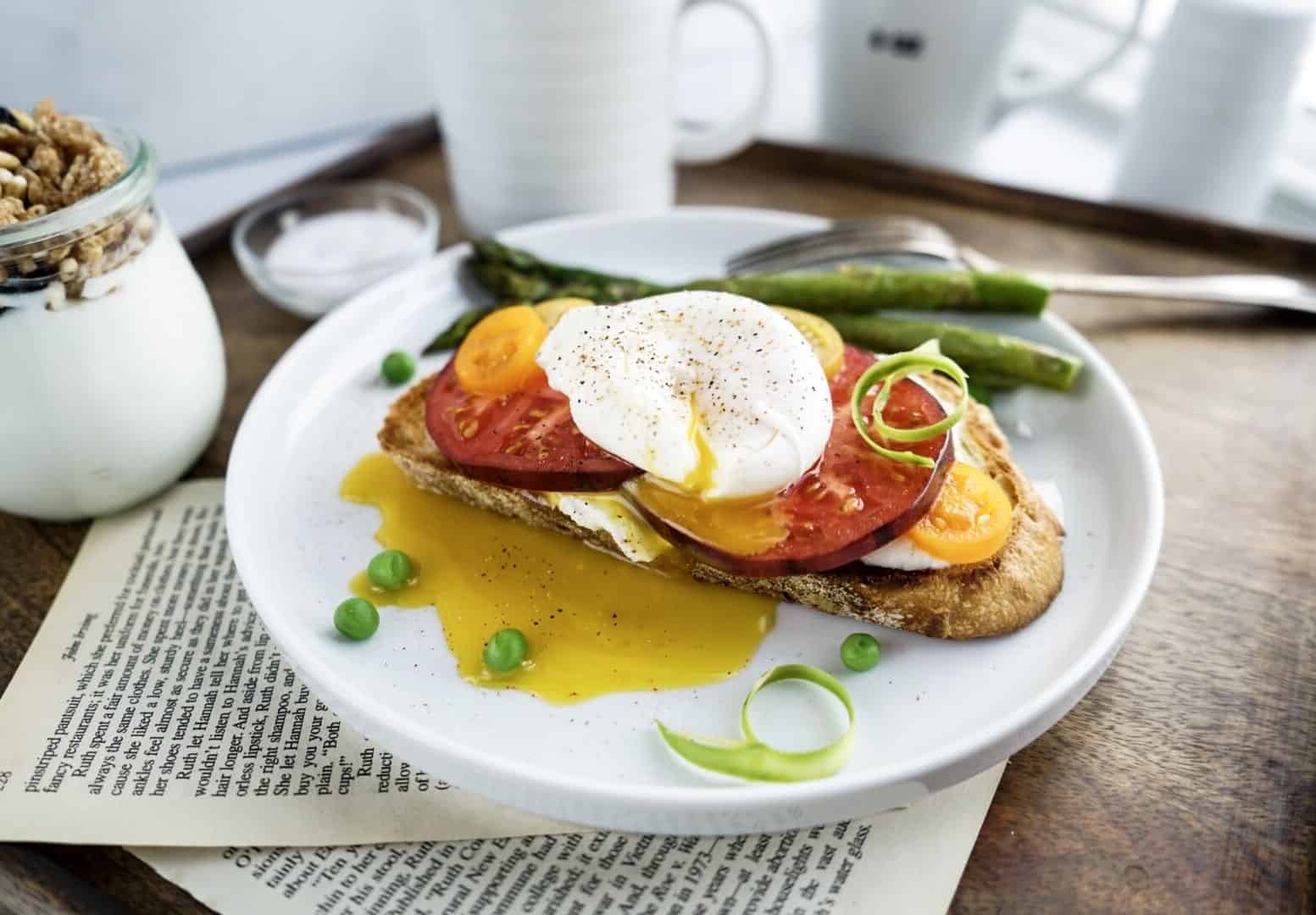 tomato toast with poached egg yolk punctured on tomato toast with poached egg
