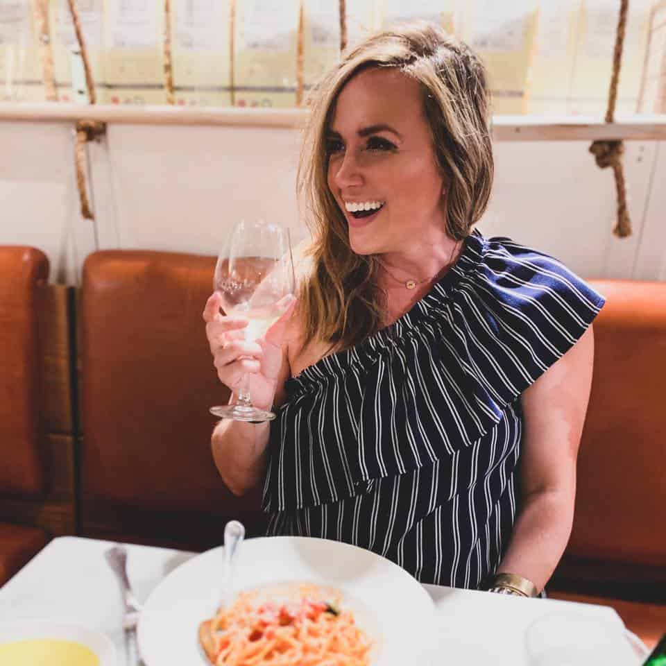 Spaghetto al Pomodoro dining at eataly with a glass of wine in hand
