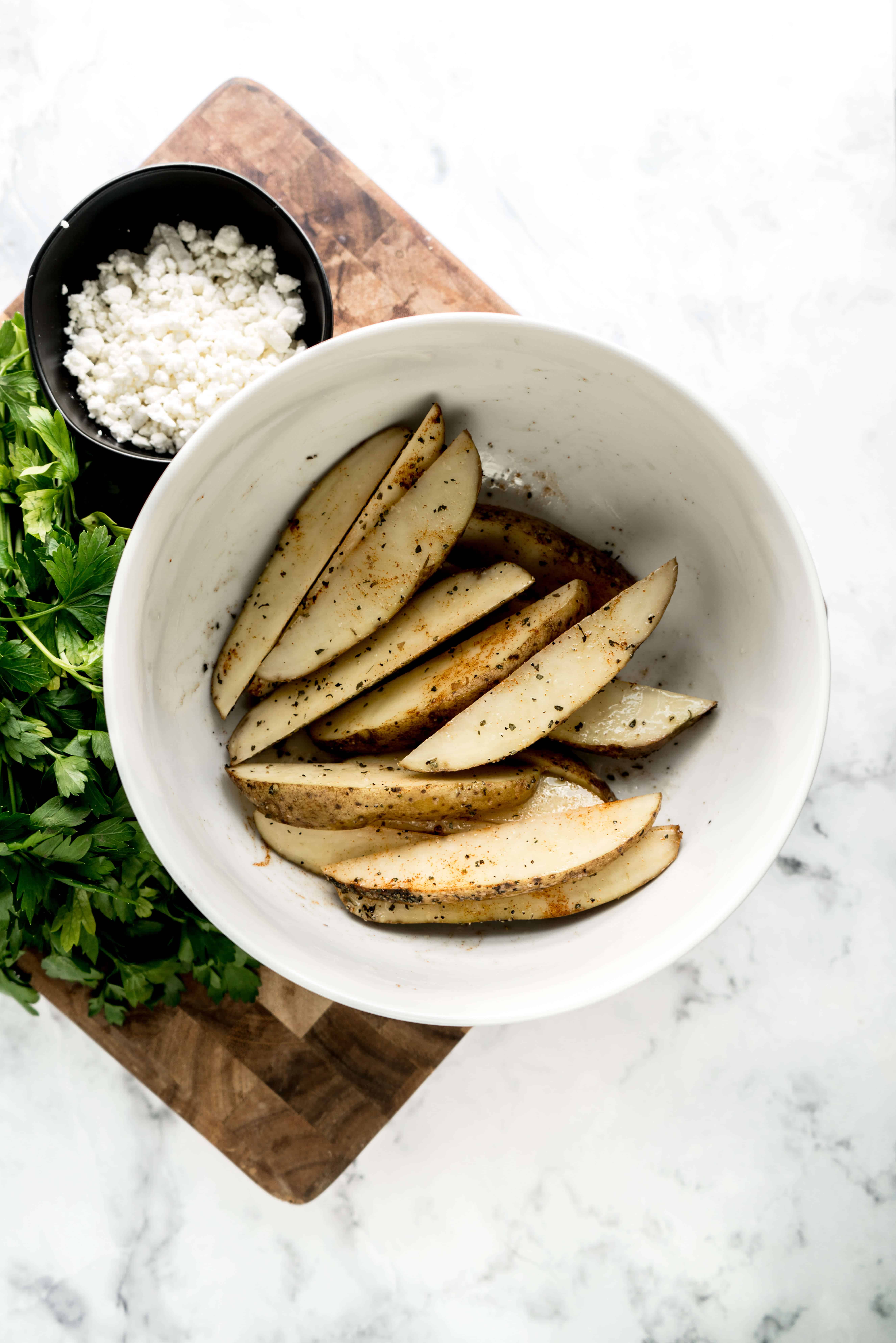 air fryer greek french fries seasoned potato wedges in bowl on cutting board
