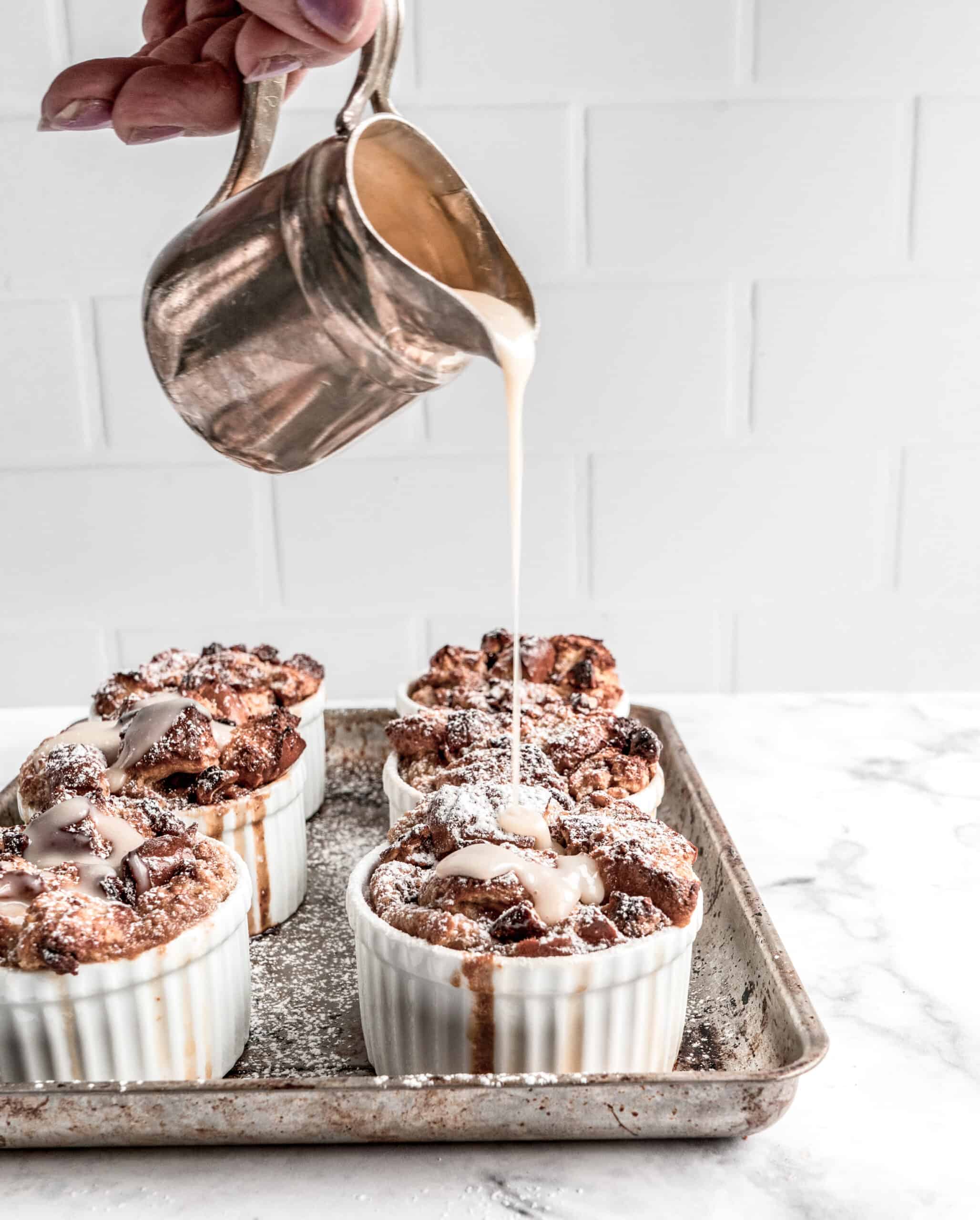 bourbon bread pudding bourbon sauce being poured on espresso breadpudding in individual ramekins