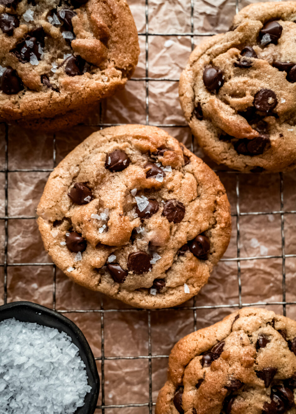chocolate chip cookies on cooling rack and a small bowl of flaky salt