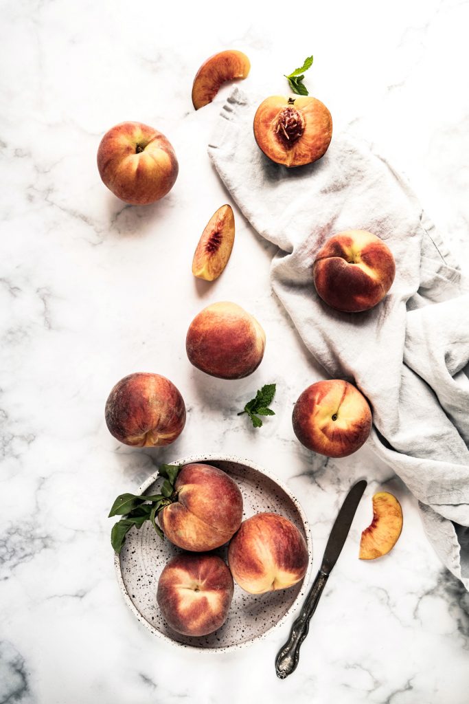 peaches in bowl and some on marble slab