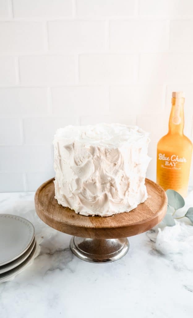 bananas foster cake on cake stand with rum bottle behind
