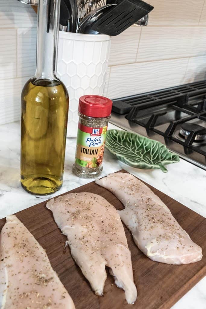 Raw chicken for Tuscan style chicken seasoned on cutting board