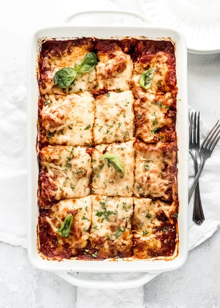 baked lasagna sliced into pieces in baking dish