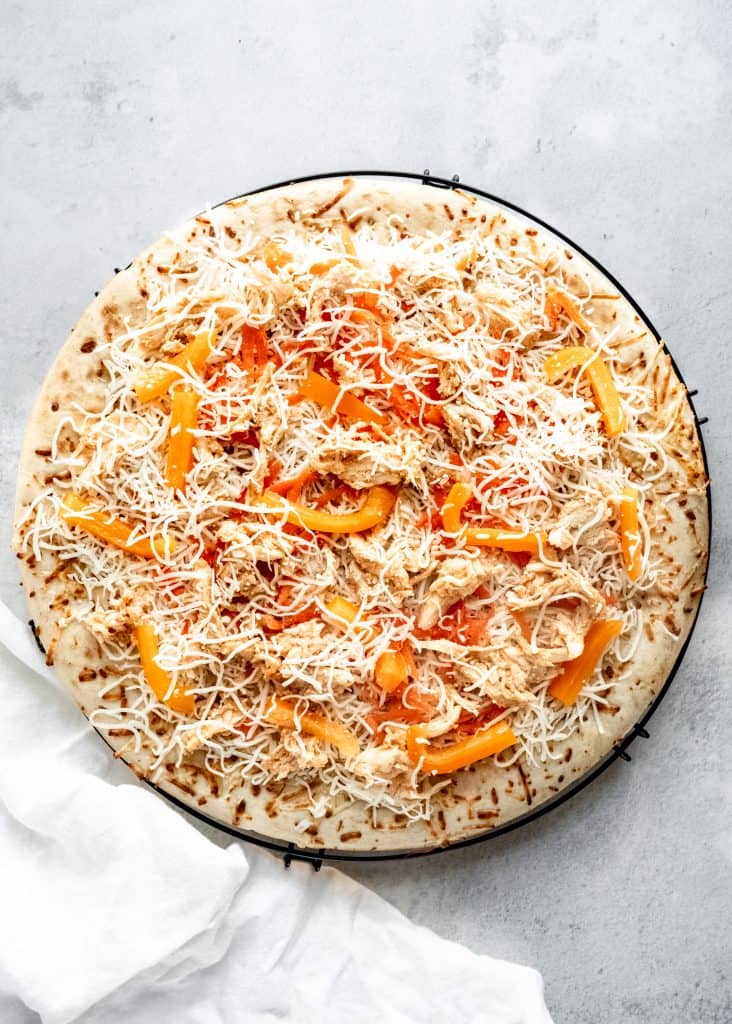 thai chicken pizza before going into the oven on cooling rack