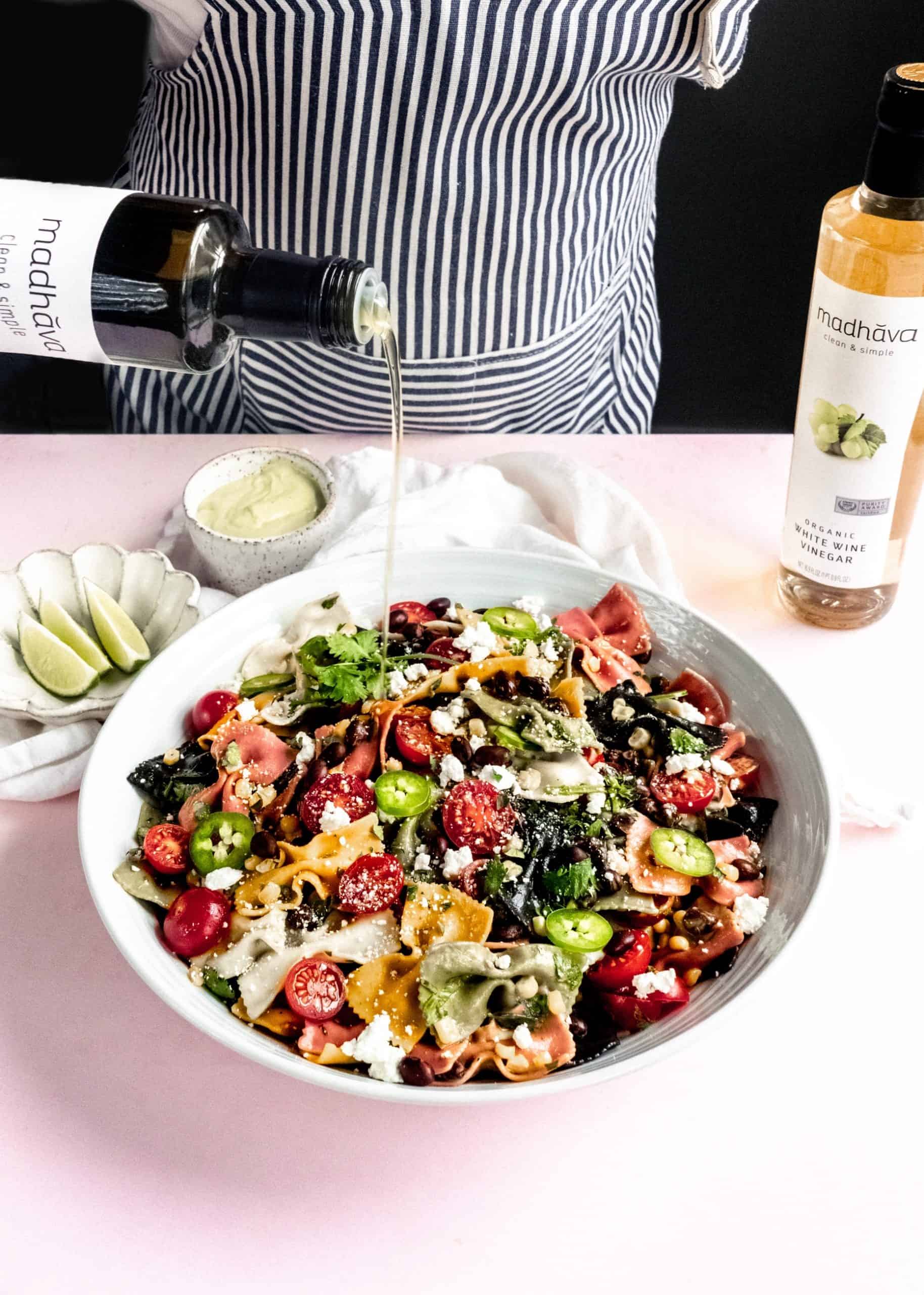 olive oil being poured on mexican pasta salad