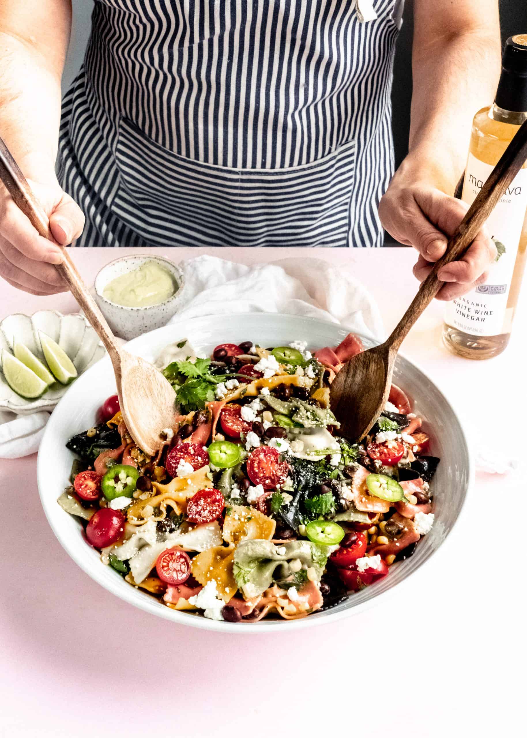 mexican pasta salad being tossed in serving bowl