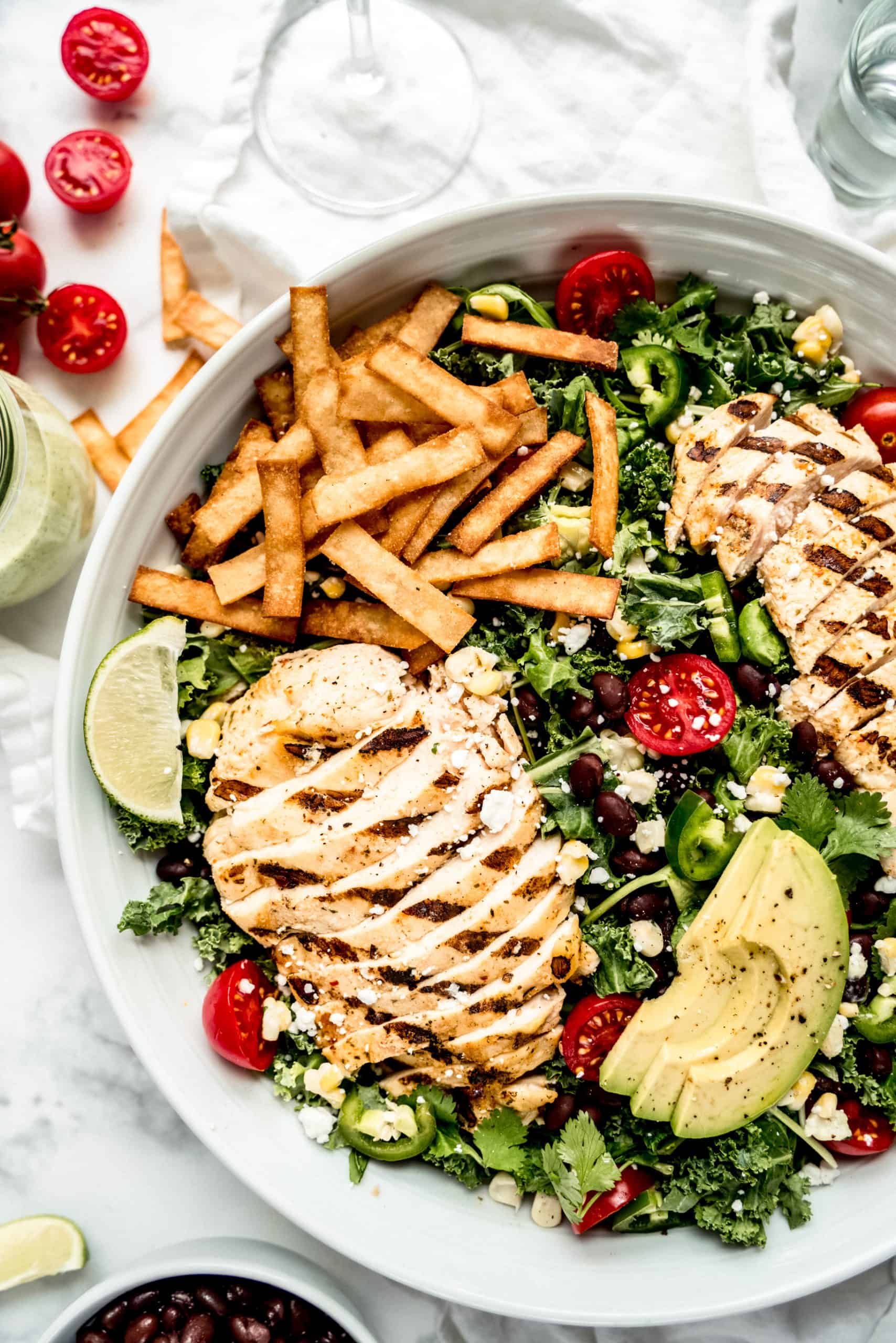 close up of chicken and tortilla strips in grilled chicken taco salad in large bowl