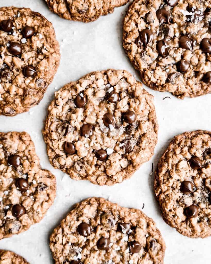 Chewy Oatmeal Chocolate Chip Cookies baked on a parchment paper lined cookie sheet.
