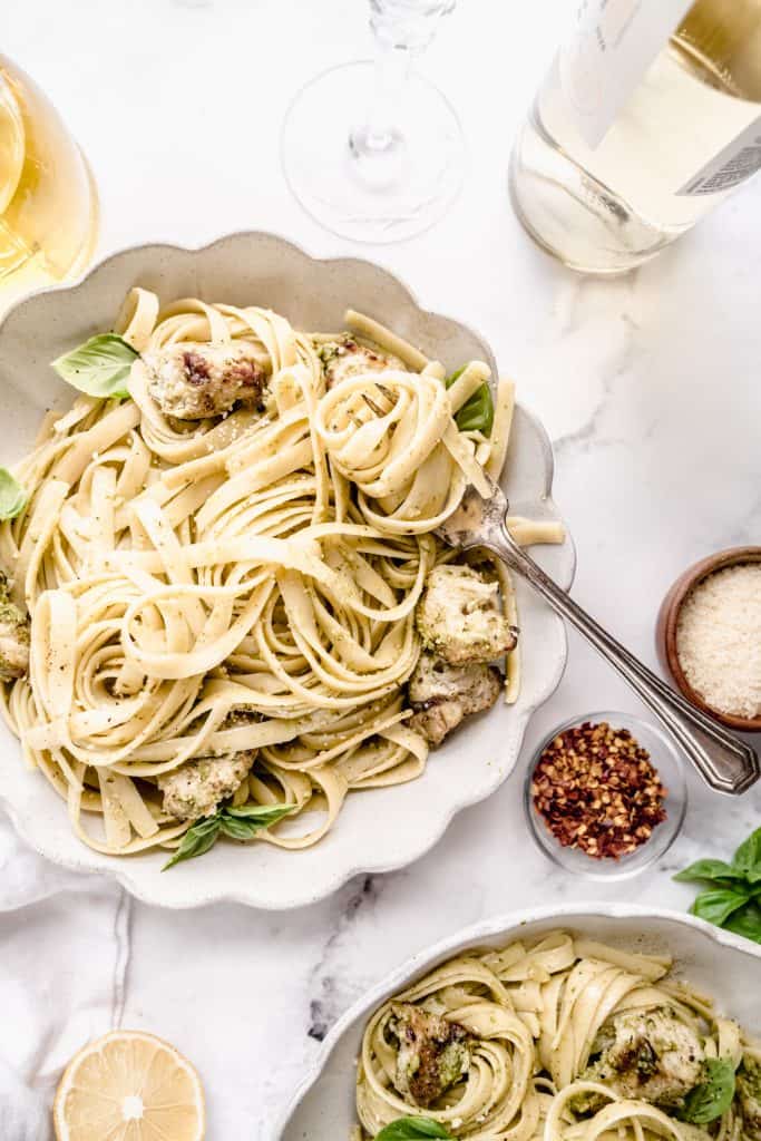 chicken pesto pasta in scalloped bowl withpasta twirled around fork
