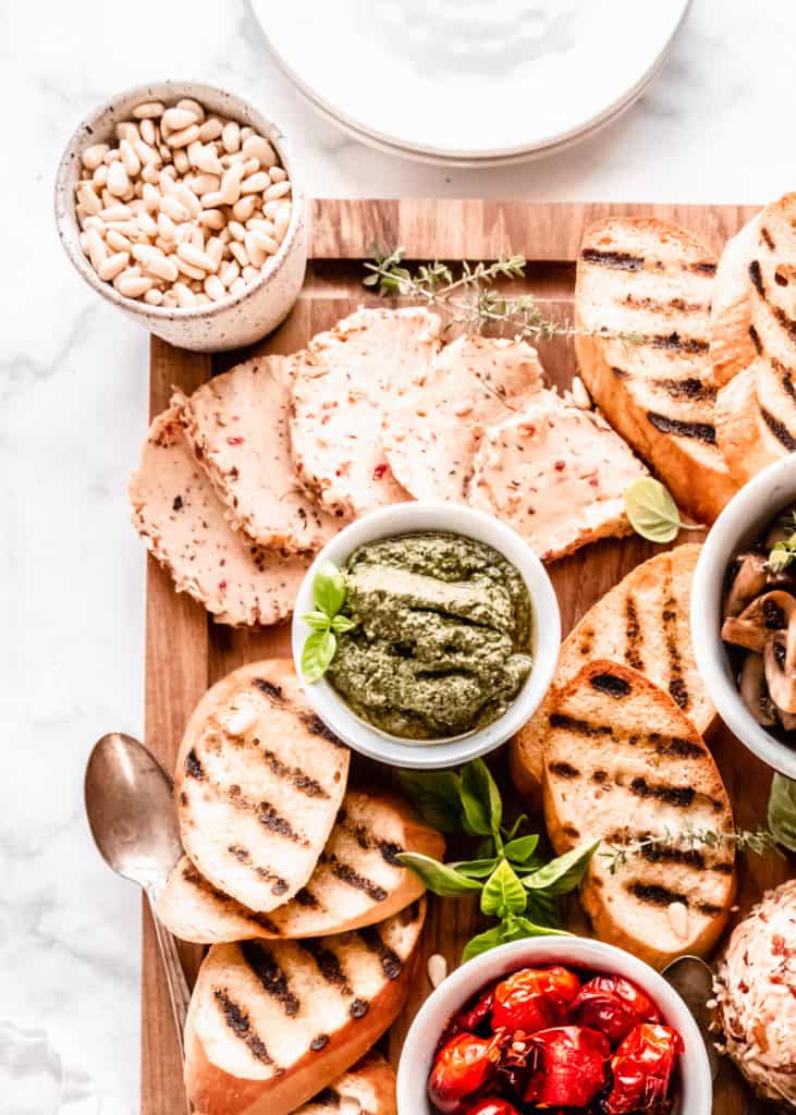 close up of pesto, on board in bowls with grilled bread surrounding