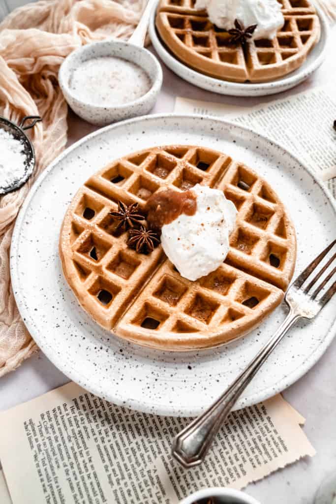 close up shot of apple butter waffles garnished with cinnamon whipped cream and apple butter on plate