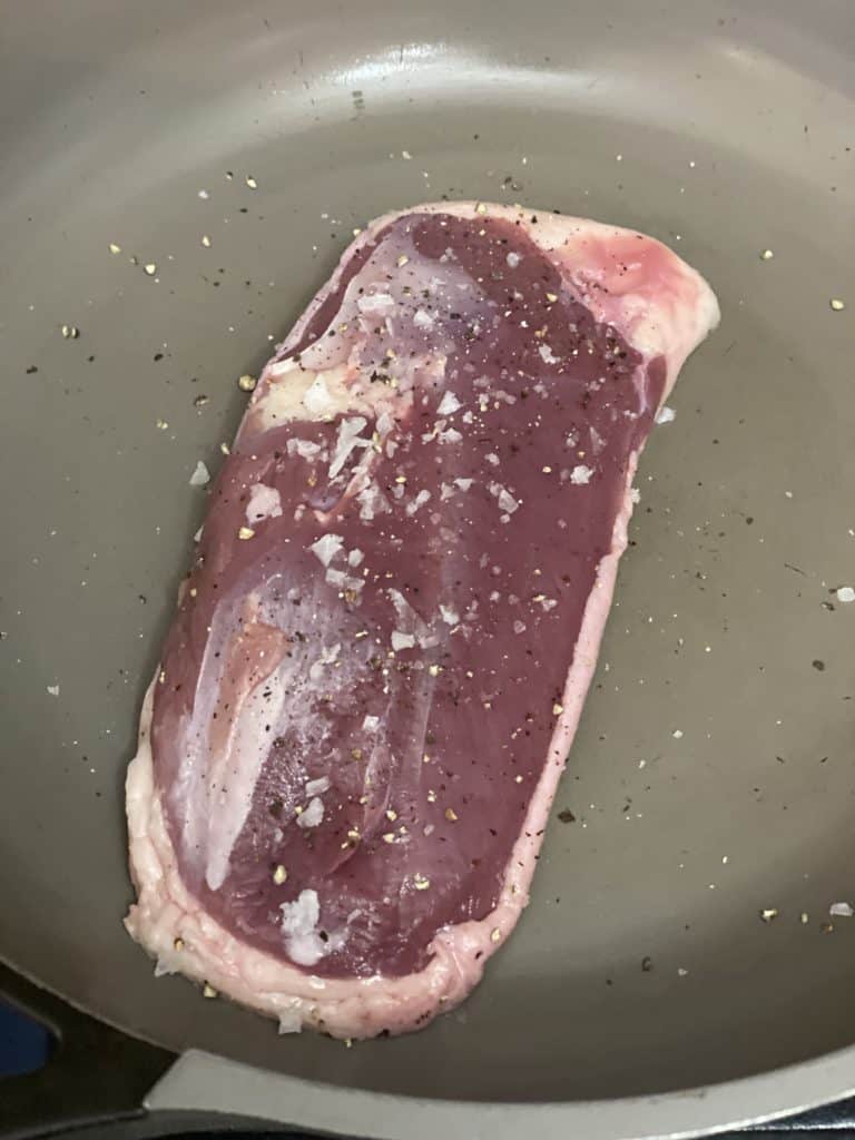 raw duck breast seasoned with salt and pepper in cold non stick pan.