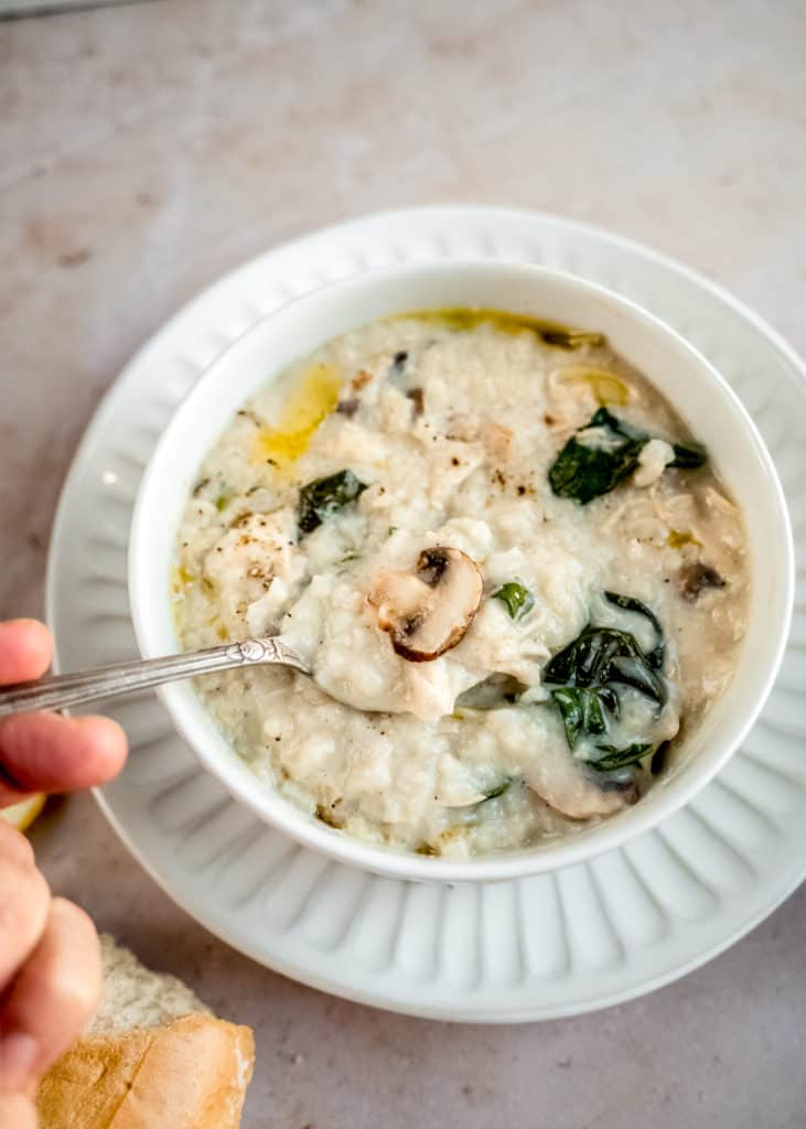 hand holding spoon scooping chicken lemon rice soup