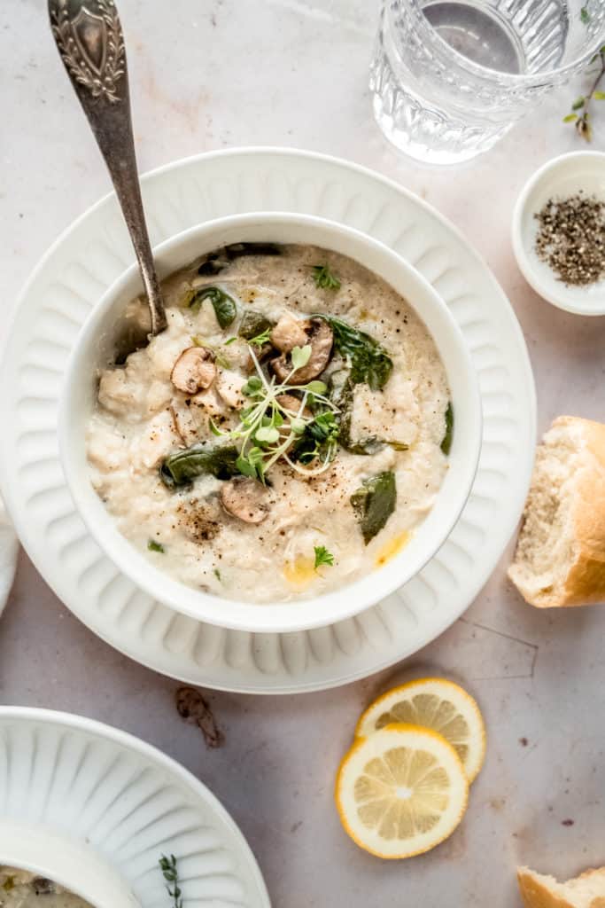 chicken lemon rice soup garnished with microgreens in bowl with spoon in the soup