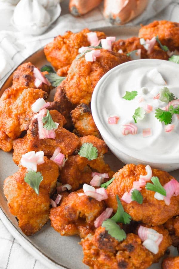 spicy roasted cauliflower bites on plate with dip in bowl in middle