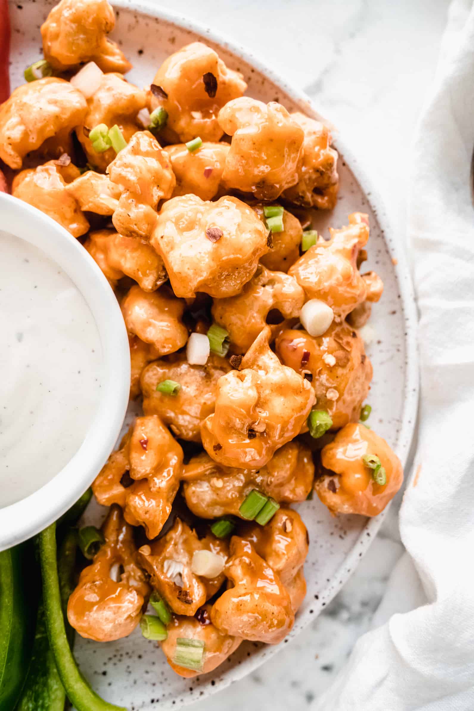 air fryer bang bang cauliflower on speckled plate with dip in middle
