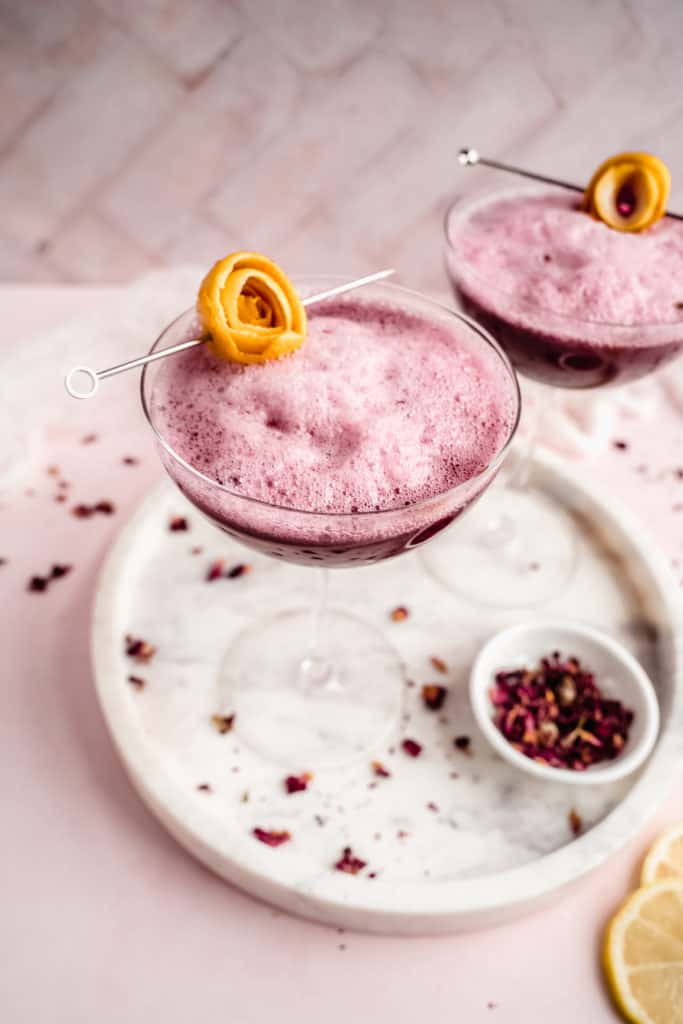 beet ginger beer mocktail in coupe glass garnished with lemon rosette on marble serving platter