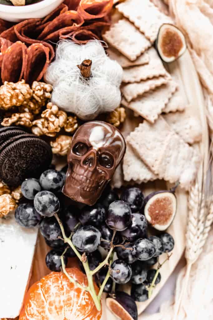 close up of chocolate skull and black grapes on halloween charcuterie board