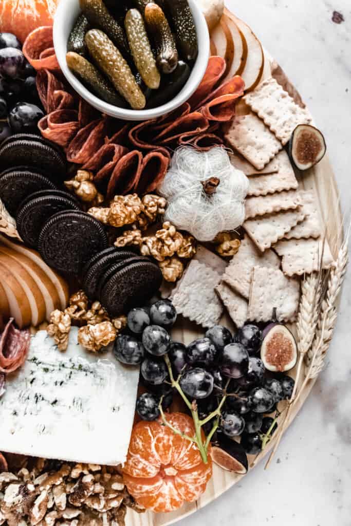 close up of crackers, blue cheese and black grapes on halloween charcuterie board