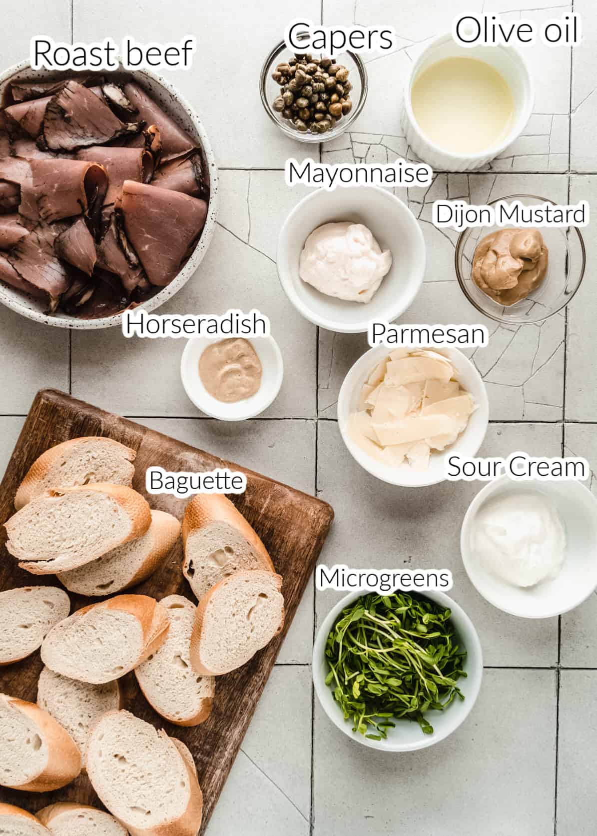 Need a simple yet elegant holiday appetizer? Look no further than this easy to make Roast Beef Crostini, perfect for parties! ingredients for roast beef crostini in bowls on tiled surface