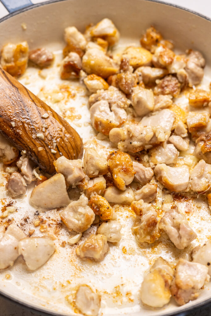 diced chicken being cooked in saute pan for hot honey chicken bowls